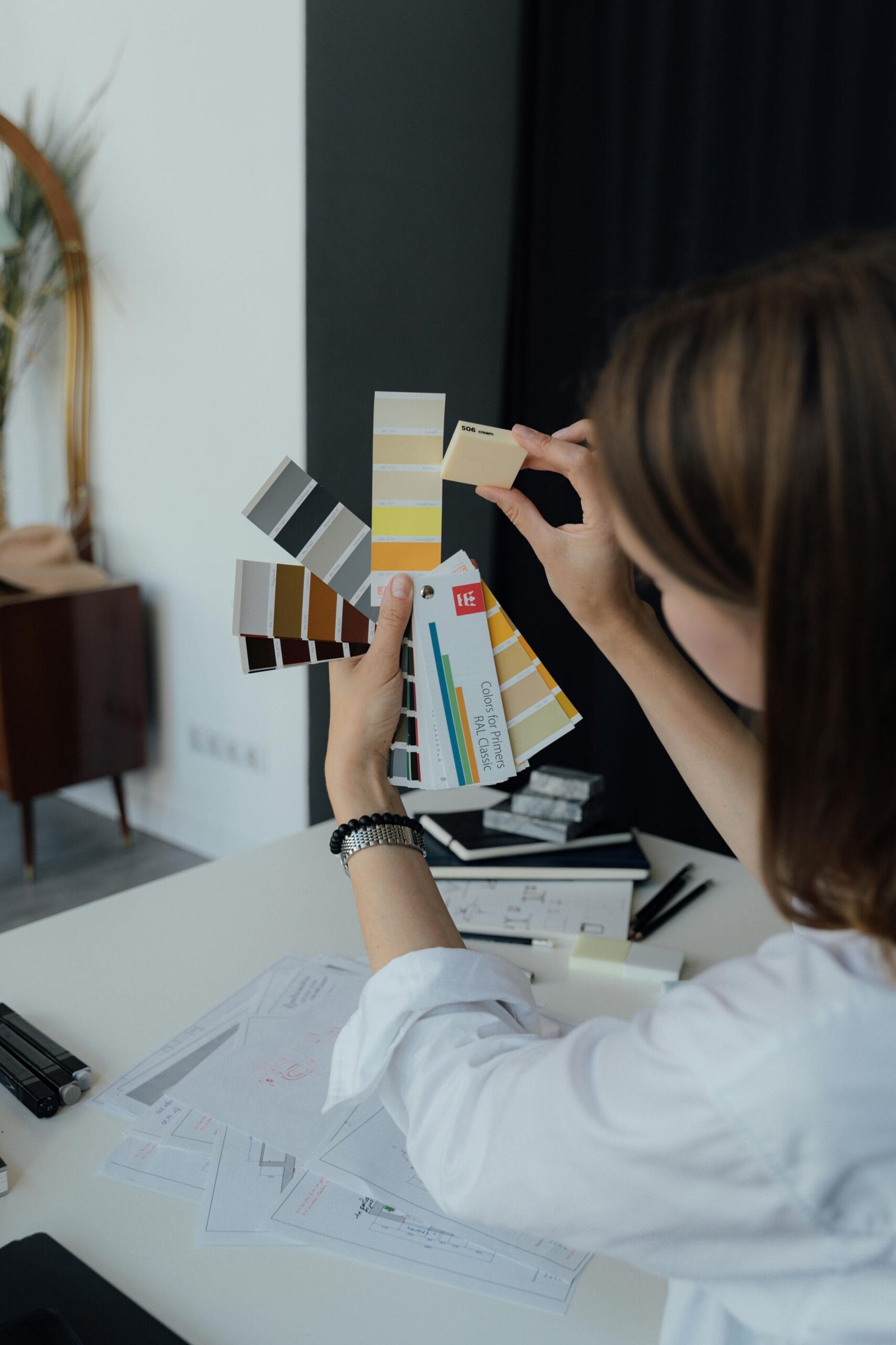 Professional interior designer examining color sample swatches at a workspace desk.