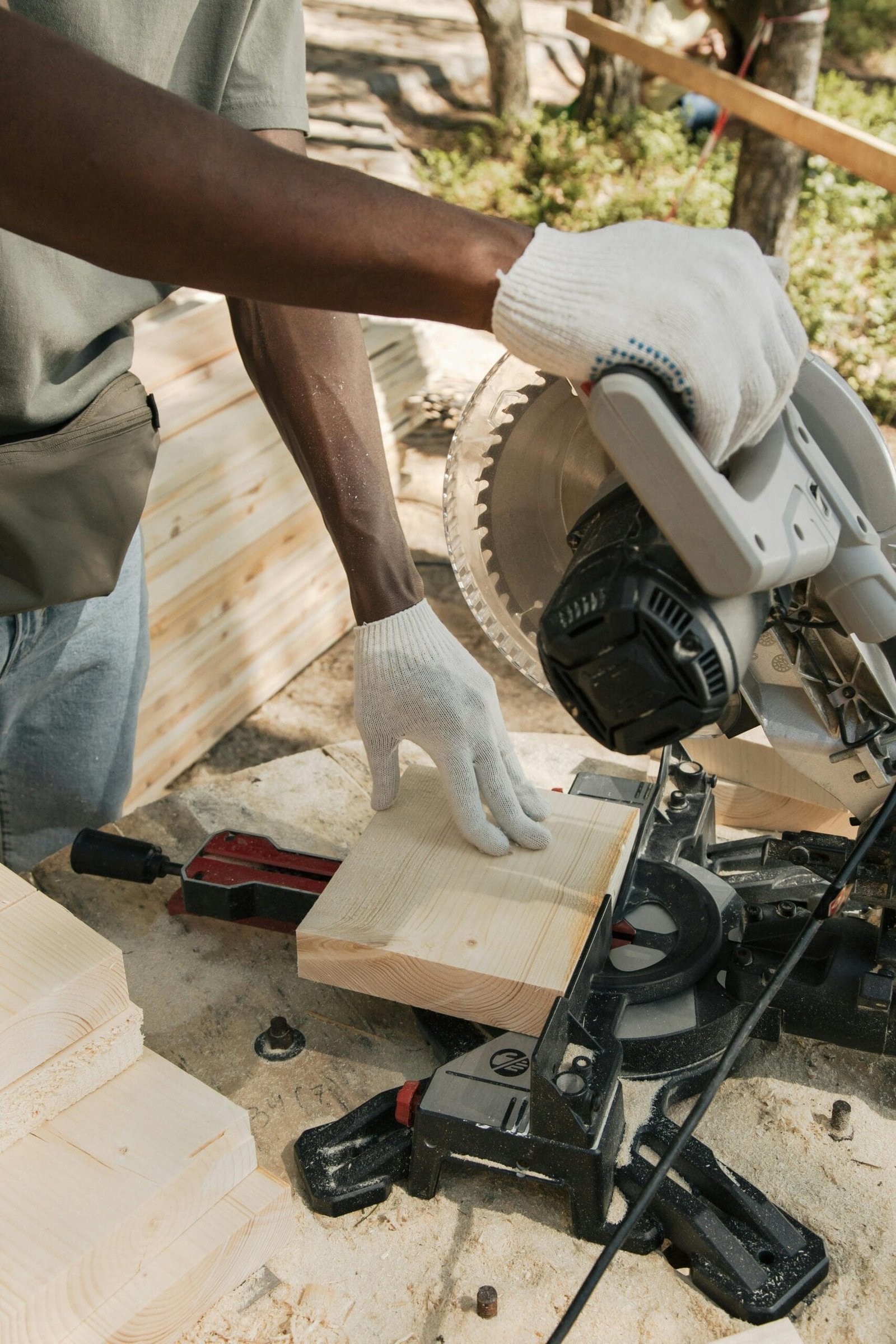 A carpenter cuts wood with a circular saw outdoors, showcasing skilled craftsmanship.