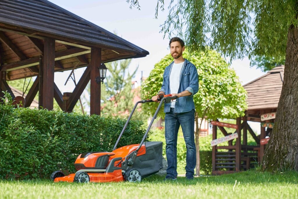 YARDMAX 22-Inch Self-Propelled Gas Lawn Mower in action on uneven terrain, highlighting its high-wheel design and mulching capabilities.