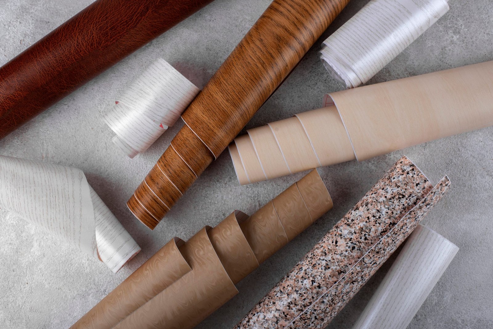 Stick and peel wallpaper installation on a living room accent wall, showcasing a marble texture with tools like a smoothing tool and utility knife in the background.
